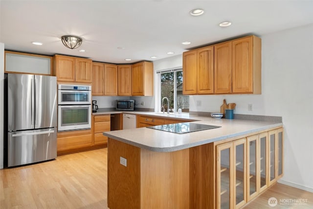 kitchen with light countertops, recessed lighting, light wood-style flooring, a peninsula, and stainless steel appliances