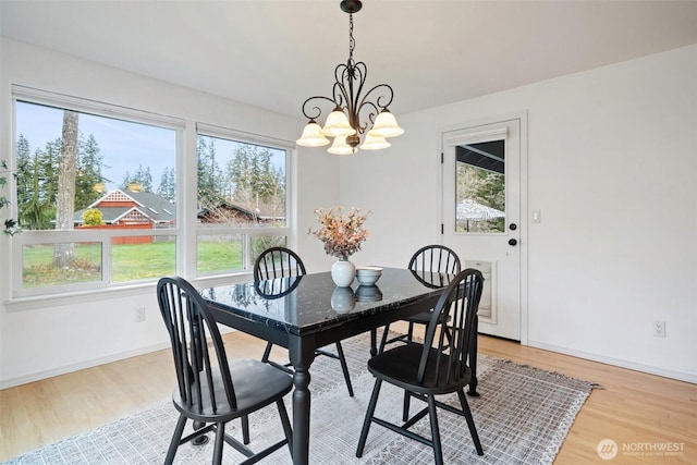 dining area featuring a notable chandelier, baseboards, and light wood-style floors