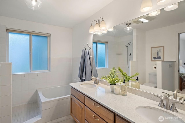 bathroom with visible vents, toilet, tiled shower, and a sink