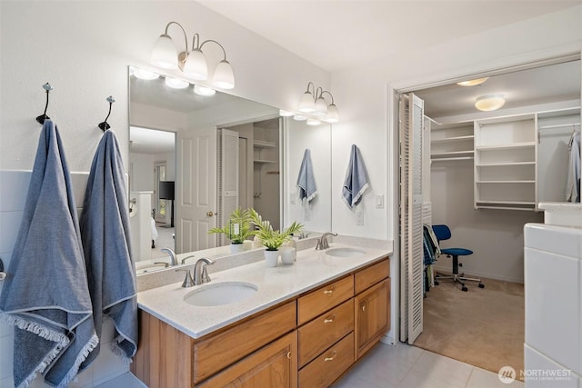 bathroom featuring double vanity, a spacious closet, tile patterned floors, and a sink