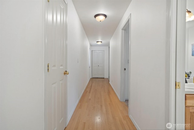 corridor featuring light wood-type flooring and baseboards