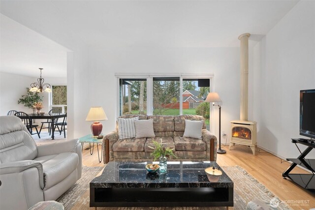 living room featuring a wood stove, a notable chandelier, and light wood-type flooring