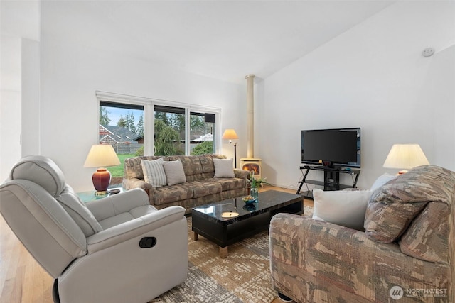 living room with high vaulted ceiling, wood finished floors, and a wood stove