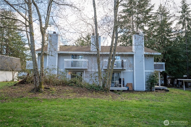 rear view of property with a yard, a chimney, and a balcony