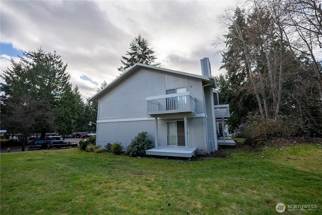 back of property featuring a chimney and a lawn