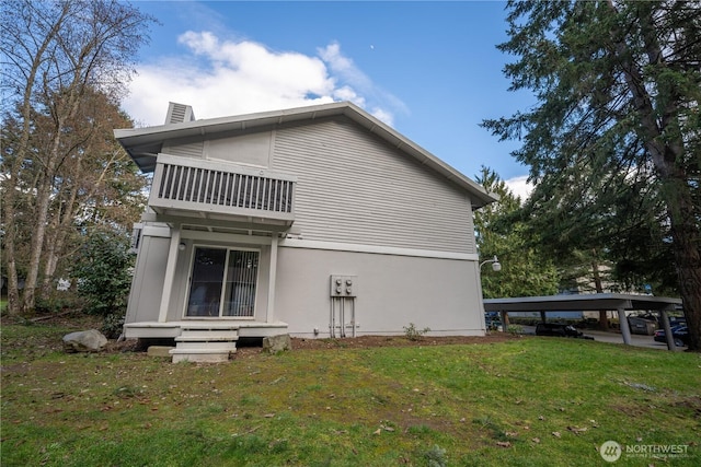 back of house featuring a chimney, a yard, and a balcony