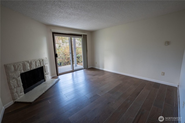 unfurnished living room featuring a textured ceiling, a fireplace, dark wood finished floors, and baseboards