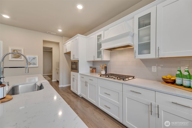 kitchen with built in microwave, sink, white cabinets, and stainless steel gas cooktop