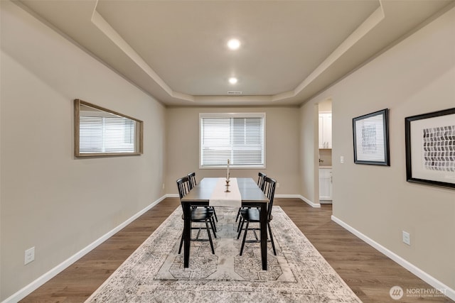 dining area featuring hardwood / wood-style floors and a tray ceiling