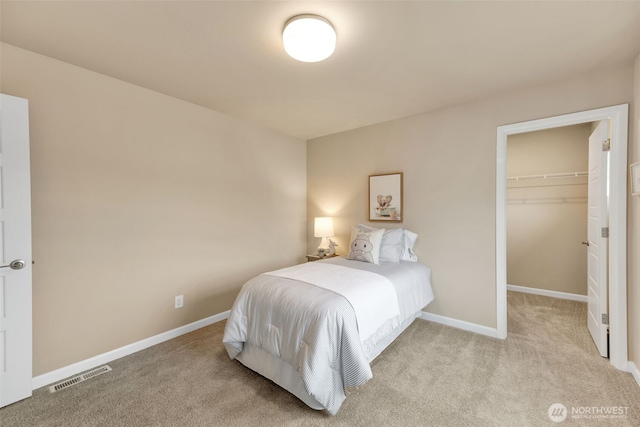 bedroom featuring light carpet, a spacious closet, and a closet