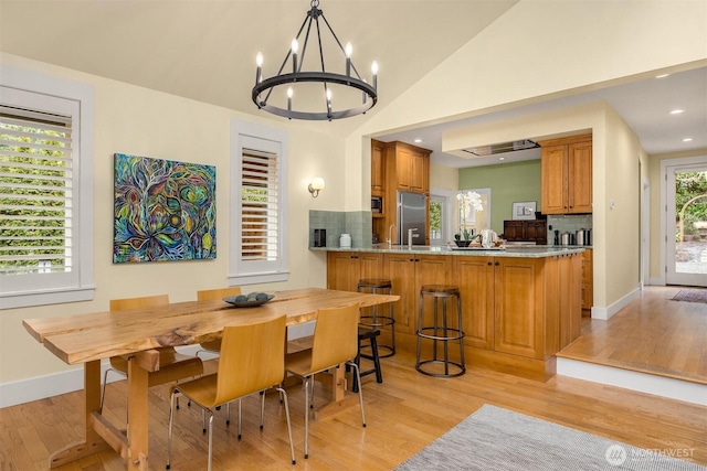 dining room featuring light hardwood / wood-style floors, vaulted ceiling, and a chandelier