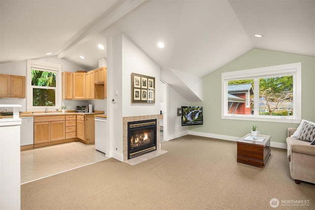 interior space featuring vaulted ceiling with beams, light brown cabinetry, dishwasher, light carpet, and a fireplace