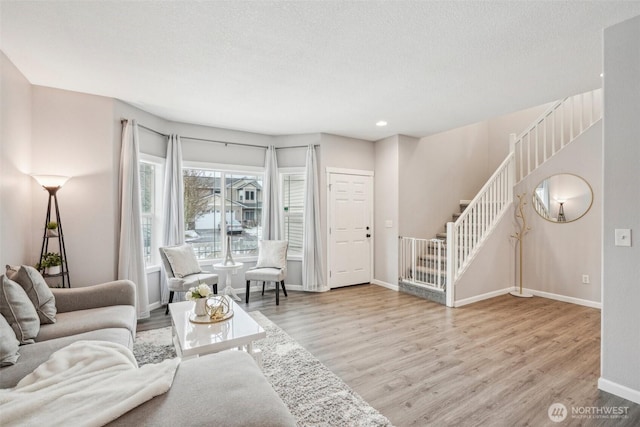 living area with light wood finished floors, recessed lighting, a textured ceiling, baseboards, and stairs