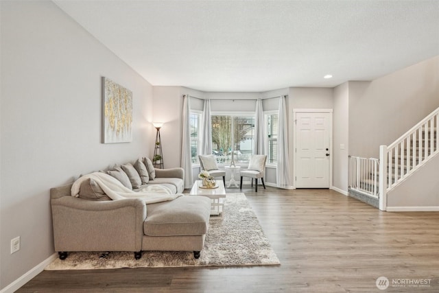 living area featuring baseboards, stairway, wood finished floors, and recessed lighting