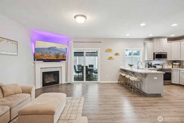 kitchen featuring a breakfast bar area, stainless steel appliances, light wood-style flooring, open floor plan, and white cabinetry