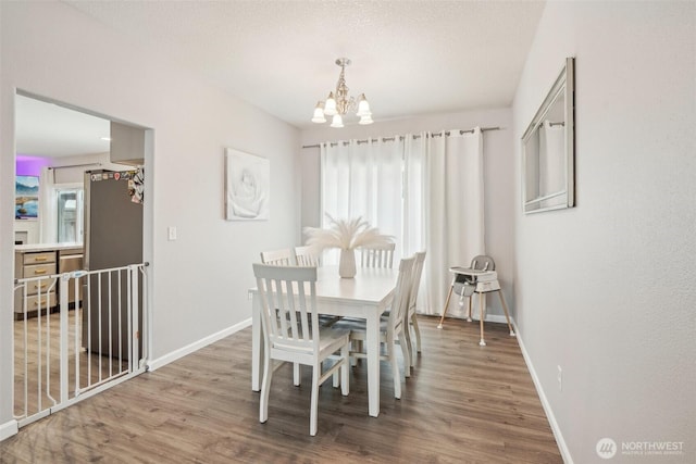 dining area featuring an inviting chandelier, baseboards, and wood finished floors