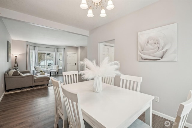 dining area featuring dark wood-style flooring, baseboards, and an inviting chandelier