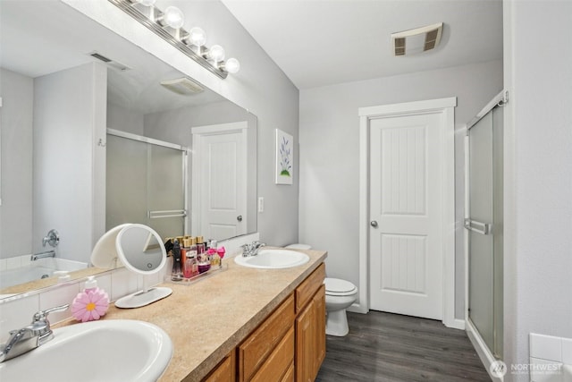 bathroom with visible vents, a sink, a shower stall, and wood finished floors