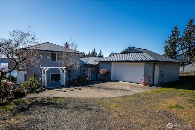 view of front of home featuring concrete driveway, metal roof, a garage, and a chimney