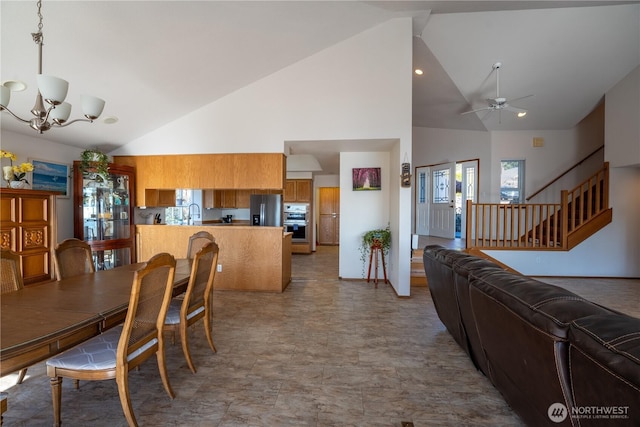 dining space featuring high vaulted ceiling, stairs, and ceiling fan with notable chandelier