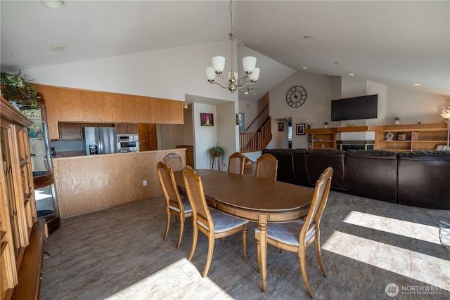 dining room featuring a notable chandelier, high vaulted ceiling, and stairs