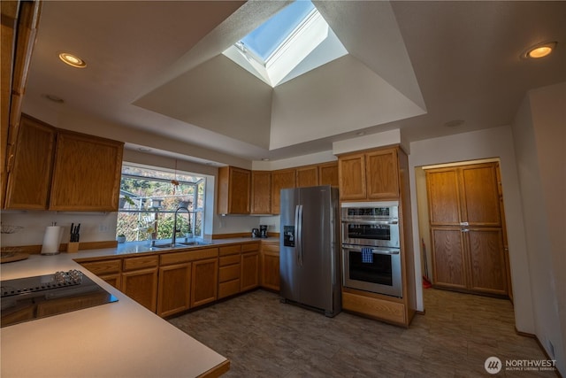 kitchen with a sink, stainless steel appliances, brown cabinets, and light countertops