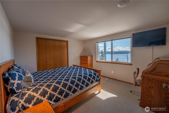 carpeted bedroom with a closet, visible vents, and baseboards