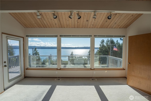 unfurnished sunroom with vaulted ceiling, wooden ceiling, track lighting, and a water view