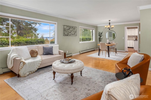 living area with ornamental molding, light wood finished floors, baseboard heating, and a chandelier