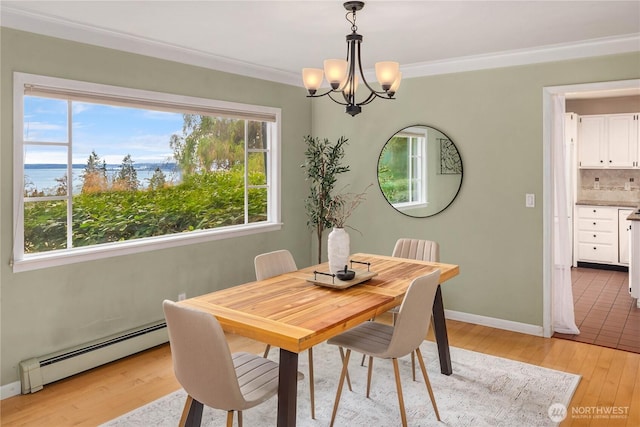 dining area featuring a baseboard heating unit, crown molding, baseboards, and light wood finished floors