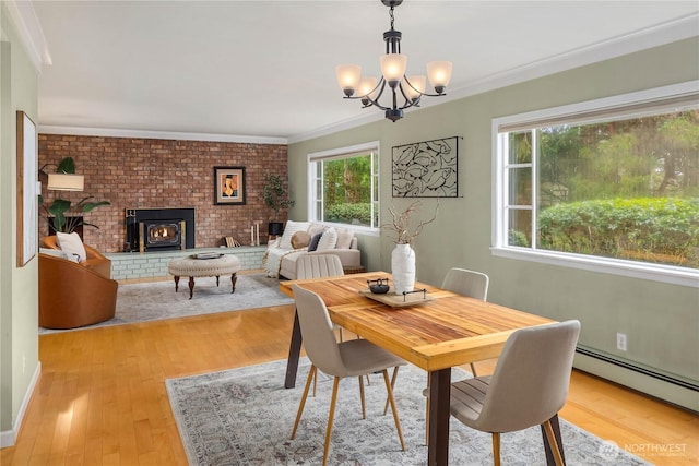 dining space with baseboard heating, an inviting chandelier, wood finished floors, and ornamental molding