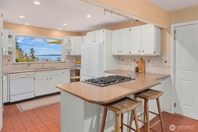 kitchen featuring a sink, a peninsula, white cabinets, white appliances, and open shelves