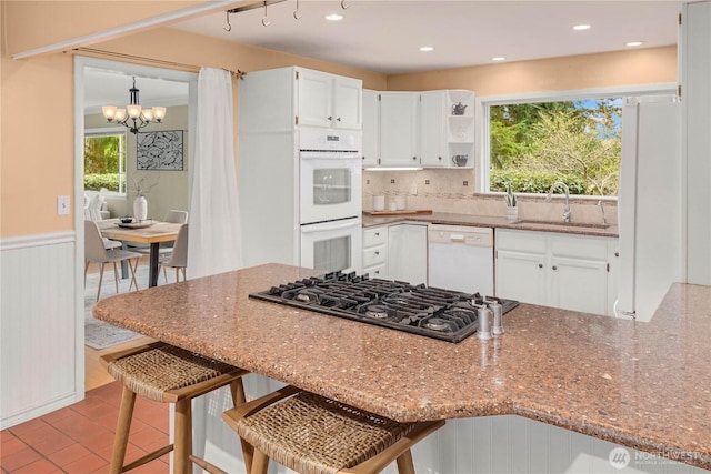 kitchen with a sink, wainscoting, white cabinets, white appliances, and open shelves