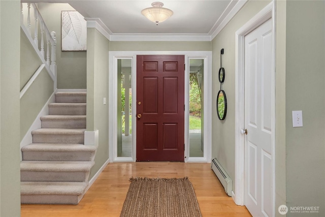 foyer featuring a baseboard heating unit, wood finished floors, stairs, and ornamental molding