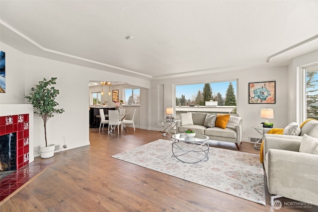 living room with a tiled fireplace, dark wood-type flooring, and plenty of natural light