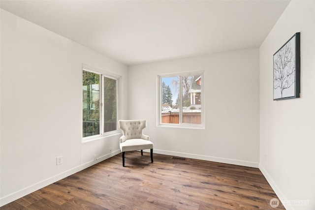 living area featuring a healthy amount of sunlight and dark hardwood / wood-style flooring