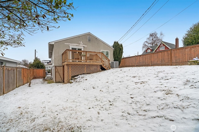 snow covered back of property with cooling unit and a deck