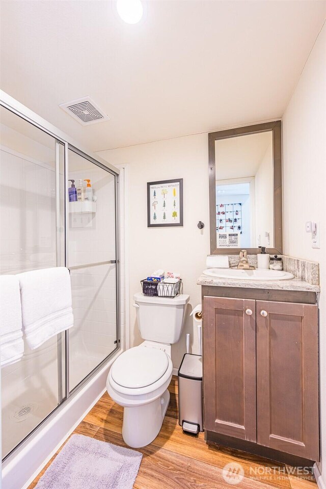 full bathroom featuring visible vents, toilet, a stall shower, vanity, and wood finished floors