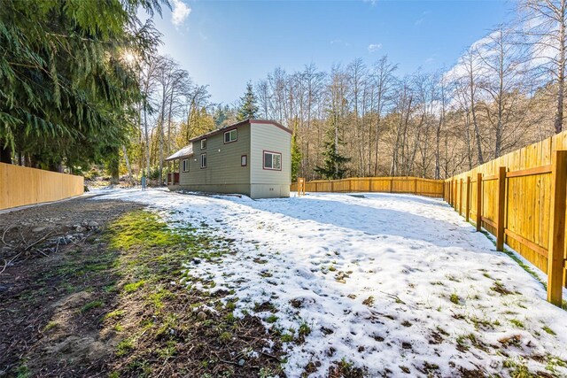 snowy yard with a fenced backyard