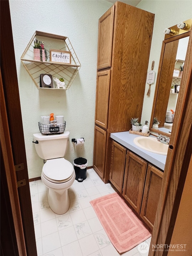 bathroom featuring toilet, baseboards, and vanity