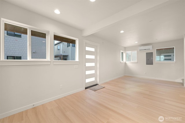 interior space with beamed ceiling, electric panel, a wall mounted AC, and light hardwood / wood-style floors