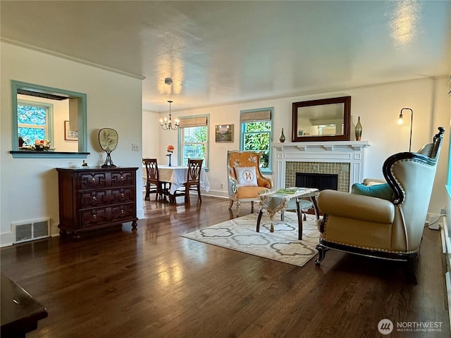 sitting room featuring a tile fireplace, dark hardwood / wood-style flooring, and a notable chandelier