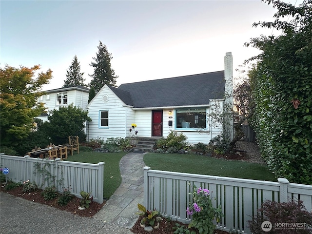 view of front facade featuring a fenced front yard, a chimney, and a front yard