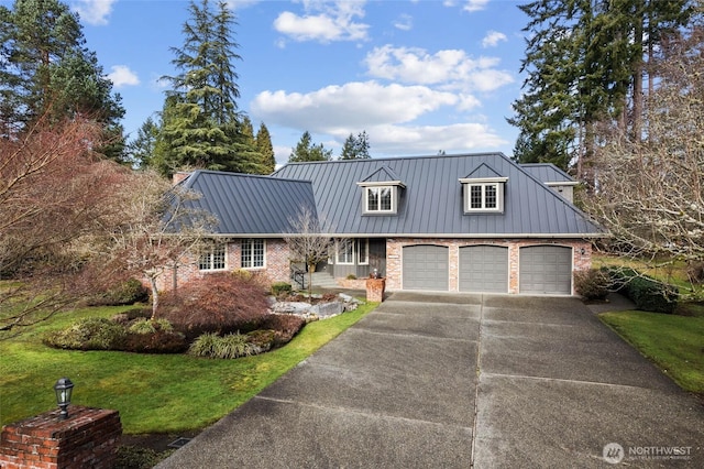 view of front of house featuring metal roof, driveway, brick siding, and a front yard