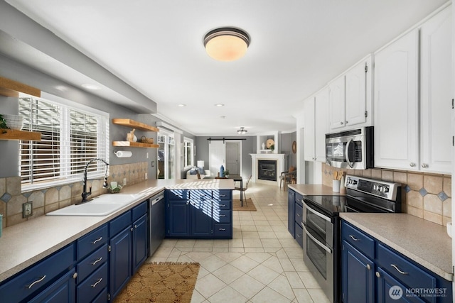 kitchen with open shelves, stainless steel appliances, white cabinets, a sink, and a peninsula