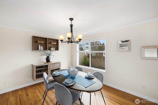 dining area with baseboards, crown molding, an inviting chandelier, and light wood-style floors