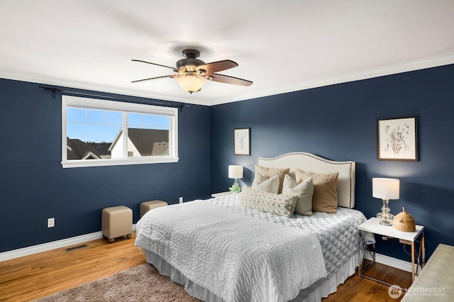 bedroom featuring baseboards, crown molding, visible vents, and wood finished floors