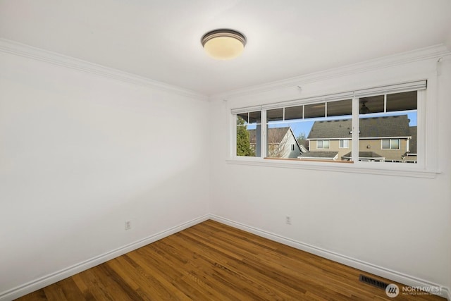 spare room with crown molding, wood finished floors, visible vents, and baseboards