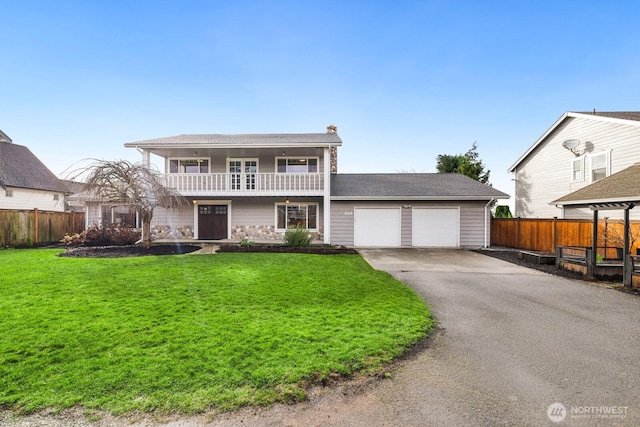 view of front of home with aphalt driveway, a front lawn, an attached garage, and a balcony