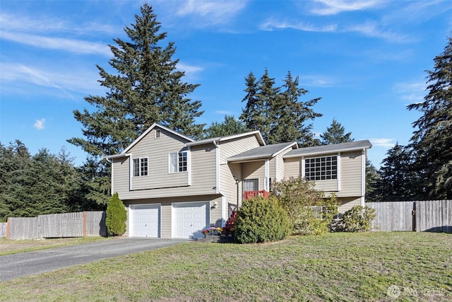 split level home featuring driveway, a front lawn, an attached garage, and fence